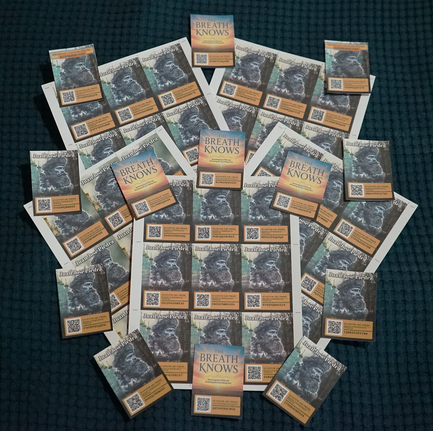 Decenas de tarjetas de Quantum Arc Press repartidas sobre una tela oscura. Algunas están selladas en fundas rígidas transparentes y otras siguen en la hoja impresa, y todas muestran una portada, un cuadro QR y un código.